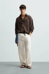 Pantalón de lino color blanco, de corte regular fit. Presenta cintura elástica, bolsillos frontales y traseros de plastrón, con cierre frontal de cremallera y botón.