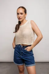 Blusa de tejido de punto calado color crema, sin mangas y corte crop.