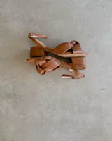 Sandalias bajas color marrón, con tira fina al tobillo y detalle de nudo en el empeine.