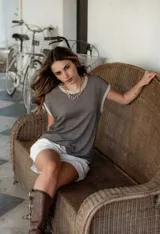 Blusa de hilo tejido a rayas horizontales en tonos gris y negro, de corte suelto y oversize, con cuello redondo y mangas cortas.