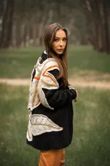 Cárdigan negro de lana con apliques de hojas en tonos beige, naranja y marrón.