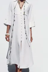 Vestido camisero largo color verde claro, confeccionado en lino. Tiene cuello solapa, escote en V, manga tres cuartos con trabilla y botón, bolsillos delanteros de plastrón, aberturas laterales en el ruedo y cierre frontal con botones.