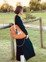 Bolso tipo tote de gamuza color camel, con aplique de estrella geométrica en tonos blanco, verde y marrón. Tiene doble asa de cuero al hombro y correa bandolera extraíble y ajustable. El interior está forrado en gamuza y cuenta con bolsillo con cierre y llavero.