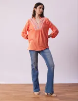Blusa blanca de poliéster y rayón con escote en V bordado y mangas tres cuartos regulables con presilla y botón.