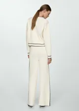 Pantalón palazzo color crema de tejido de punto fino, con cintura elástica y bandas laterales negras en contraste.