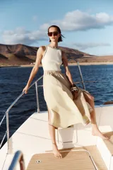 Vestido midi color beige con top blanco de cuello redondo y manga sisa con vivos negros a contraste. Cintura elástica y falda con aberturas laterales.