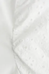 Top blanco de algodón con cuello redondo y mangas globo cortas de algodón bordado con forro de punto y ribete elástico.