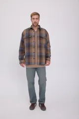 Sobrecamisa de manga larga a cuadros en tonos marrón, azul y verde. Tiene cierre con botones, bolsillos en el pecho con cierre de botón y corte relajado.