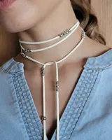 Collar marrón de cuero con cuentas doradas, con tiras finas que se atan al cuello y caen sobre el pecho.