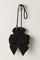 Bolso de terciopelo negro, estilo saco o fruncido, con un gran lazo decorativo en el frente. Posee una correa de hombro ajustable con herrajes dorados.
