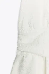 Top negro de cuello halter y escote pico con volantes en el bajo.