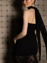 Vestido negro strapless con cuerpo fruncido y falda con tajo lateral y volados. Incluye choker al tono.