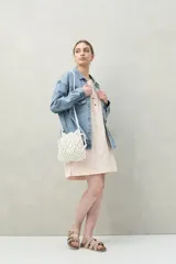 Vestido corto blanco de algodón con bordado floral en relieve, escote redondo con abotonadura frontal y mangas amplias.