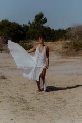 Vestido largo de color blanco, con escote en V pronunciado y tiras largas que permiten anudarlo de múltiples formas. Presenta tajo en ambos laterales y forro interno.