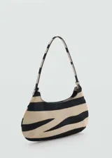 Bolso tipo baguette con estampado de cebra en tonos beige y negro. Tiene asa de hombro y cierre de botón magnético.