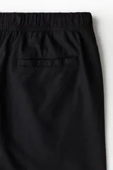 Short negro de corte recto, con cintura elástica ajustable con cordón, bolsillos laterales y bolsillo trasero.