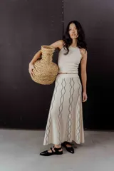 Conjunto de top y pollera color crema con ribetes negros. El top es musculosa con cuello redondo y la pollera es larga con estampado abstracto.