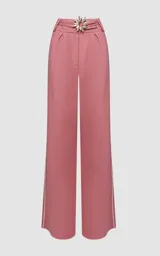 Pantalón de lino rosado de silueta amplia y fluida con detalle de hebilla metálica en forma de sol en la cintura. Su diseño de tiro alto con pliegues frontales estiliza la figura, mientras que las aberturas laterales con bordado contrastante añaden un toque sofisticado y veraniego.