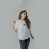 Remera blanca de algodón con estampa circular en la espalda con un globo terráqueo en color lila y texto "Bad Decisions Club Member" en negro y celeste.