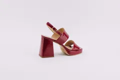 Sandalias de plataforma color borgoña, confeccionadas en charol. Tienen dos tiras anchas sobre el empeine, pulsera con hebilla al tobillo y taco cuadrado de 9 cm.