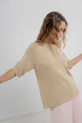 Buzo de punto color beige, de manga 3/4, calce relajado y escote redondo.