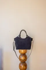 Cartera de gamuza color azul marino con doble asa corta y correa larga desmontable.