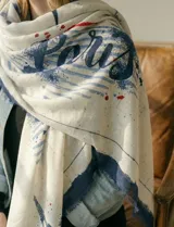 Pashmina estampada en tonos crudos y azul marino, con diseño tipográfico que incluye la palabra "Paris" y detalles de pinceladas.