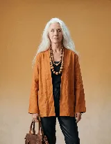Chaqueta tipo kimono sin cuello, confeccionada en tela estampada con patrón floral en tonos beige y marrón. Presenta un frente abierto con posibilidad de ajuste mediante lazo.