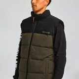 Chaleco acolchado Caterpillar, color marrón con parte superior negra, cierre frontal con cremallera, cuello alto y bolsillos laterales con cierre.