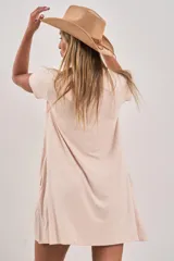 Vestido corto de manga corta, color beige claro, con corte holgado y bolsillos laterales.