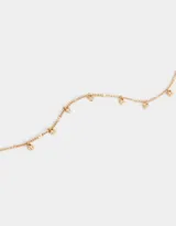 Collar corto dorado con cadena de eslabones y dijes colgantes en forma de corazón con incrustaciones de cristal.