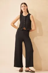 Pantalón palazzo negro de tela de punto arrugada.