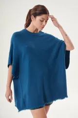 Poncho celeste de tejido de punto con cuello redondo y terminación desflecada.
