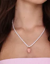 Cadena corta de perlas sintéticas con dije de moño y racimo de uvas, con cierre de mosquetón.