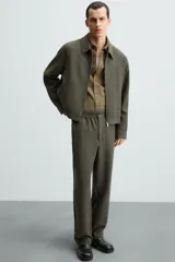 Pantalón verde oscuro de corte recto, con cintura elástica, bolsillos laterales y un bolsillo trasero. Cierre frontal con cremallera y botón.