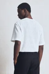 Remera blanca de punto calado con textura tipo crochet, corte estándar, cuello redondo y mangas cortas.