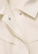 Chaleco color crema de denim con cuello camisero, cierre frontal con botones ocultos, sin mangas y corte recto.