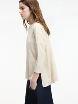 Sweater color crema de corte amplio, con cuello redondo y tajos laterales.