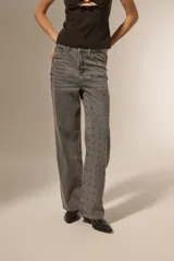 Pantalón gris de denim con corte recto, tiro alto y apliques de tachas cuadradas plateadas en los laterales.