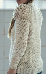 Sweater tejido a crochet color crudo, con cuello redondo, mangas largas y hombros abullonados.