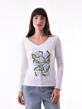 Remera blanca de manga larga con cuello en V y estampado de flores azules y hojas verdes.