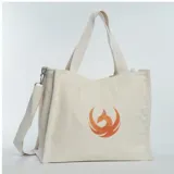 Bolso tipo shopper de tela color crema con asas cortas y correa larga desmontable. Estampado de un ave fénix color naranja.