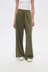 Pantalón deportivo color verde militar, de corte ancho y tiro alto, con cintura elástica y cordón ajustable. Presenta una raya blanca vertical en los laterales.