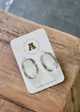 Aros colgantes plateados con forma ovalada irregular y apliques de strass.