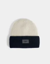 Gorro de lana tejido bicolor, blanco y azul marino, con etiqueta de goma con logo en el frente.