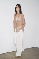 Blusa semitransparente color beige con bordados de hilo metalizado y abalorios. Tiene mangas cortas y cierre frontal con cordones.