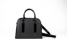 Cartera tipo tote de cuero color tostado, con doble asa corta y correa larga extraíble. Tiene cierre superior, bolsillo interno con cierre y herrajes metálicos plateados.