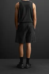 Bermuda jogger negra confeccionada en tejido de algodón con interior de rizo, cintura elástica ajustable con cordón y bolsillos laterales.