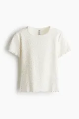 Remera blanca con estampado floral, de corte ajustado en punto suave, con ribete fino en el cuello y acabado sobrehilado en mangas y bajo.