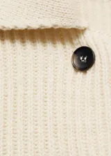 Chaqueta color crema de tejido de punto de canalé, con cuello camisero, cierre de botones en la parte delantera y manga larga.